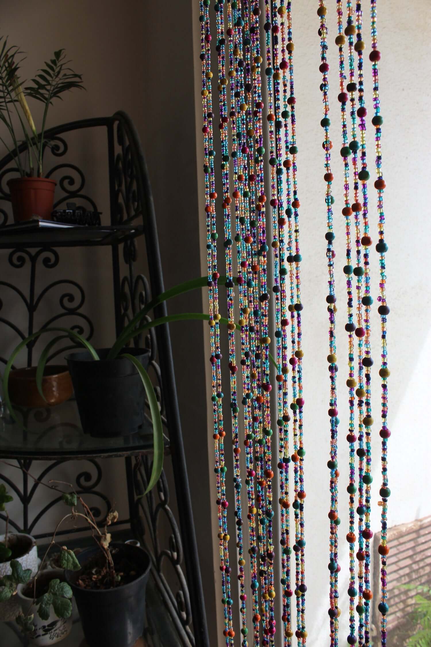 Handmade colorful glass bead strands with jingle bells—perfect for doorways or wall décor. Eco-friendly and crafted by women's artisans in India.